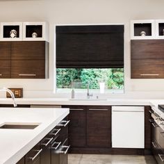 a kitchen with white counter tops and brown cabinets