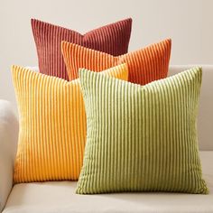 four different colored pillows sitting on top of a couch