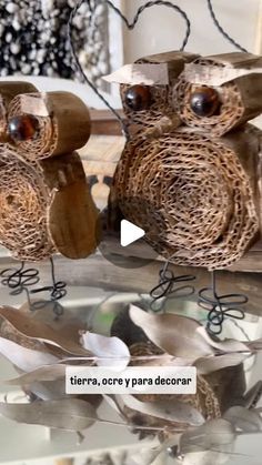 two wooden owls sitting on top of a glass table