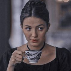 a woman holding a coffee cup in her right hand and looking at the camera with an intense look on her face