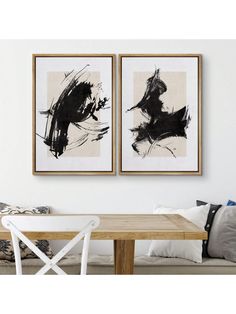 two black and white paintings hanging above a wooden table