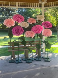 some pink and white flowers are in vases on a bench under a gazebo