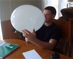 a man sitting at a table with a white balloon in front of his face,