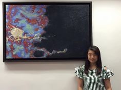 a woman standing in front of a large painting