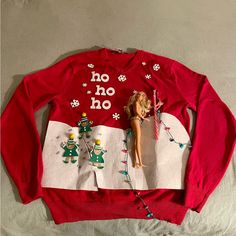 a red sweater with an image of a doll and christmas decorations on the front is laying on a bed