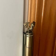 a brass dragon figurine is on top of a door handle in front of a curtain