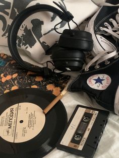 an old record, headphones, and pair of sneakers are laying on a bed