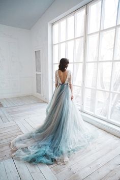 a woman standing in front of a window wearing a blue and white dress with sheer back