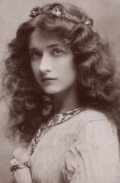 an old black and white photo of a woman with long hair wearing a tiara