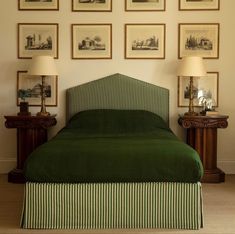 a bed with green bedspread in front of pictures on the wall above it