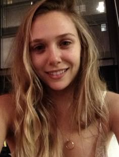 a woman with long blonde hair sitting in front of a table holding a plate of food