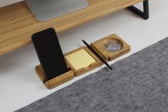 a desk with a cell phone, pen and paper holder