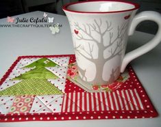 a coffee cup sitting on top of a table next to a quilted place mat