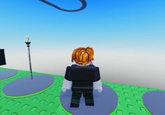 a lego figure standing in the middle of a green area with a black object on it's head