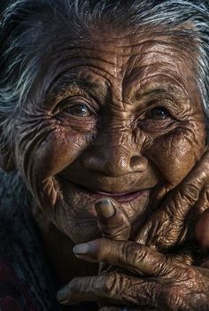 an old woman with wrinkles on her face and hands, smiling at the camera