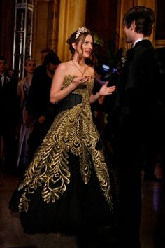 a woman in a black and gold dress standing next to a man