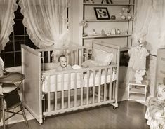 an old black and white photo of a baby in a crib with curtains on the windows