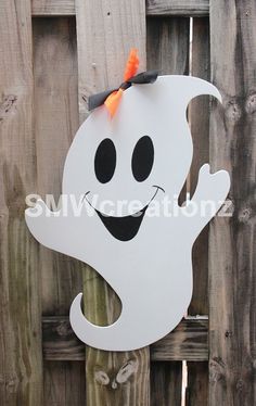 a white ghost hanging on a wooden fence