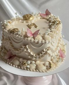 a wedding cake with white frosting and pink butterflies on the top is sitting on a pedestal