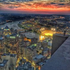 the city skyline is lit up at night, with lights on and buildings in the foreground