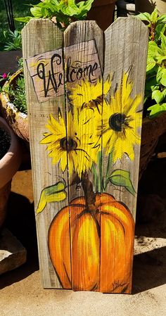 a wooden sign with sunflowers and a pumpkin painted on it's side