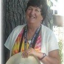 a woman holding a white hat in front of a tree