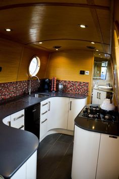 a kitchen with white cabinets and black counter tops in a boat or ship that looks like it has been built into the water