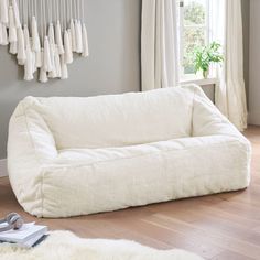 a large white dog bed sitting on top of a hard wood floor next to a window