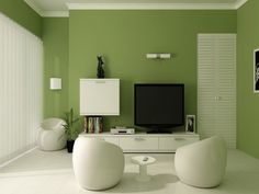 a living room with green walls, white furniture and a flat screen tv on the wall