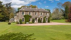 a large stone house in the middle of a lush green field