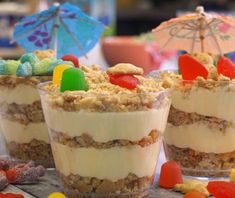 three desserts with candy and jelly beans in them sitting on a table next to an umbrella