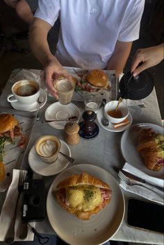 a table topped with lots of food and cups of coffee next to each other on plates