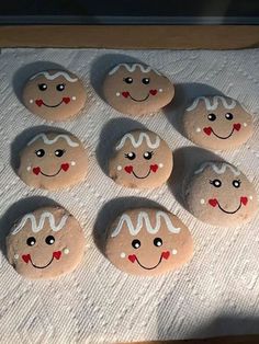 six rocks with faces painted on them sitting on a towel