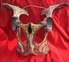 an elaborate mask is displayed on a red cloth