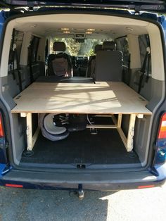 the back end of a blue van with an open hatchback and table in it