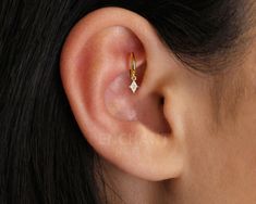 a woman's ear with a single diamond in it