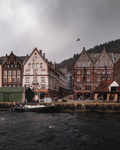 a boat is in the water next to some buildings and a bird flying over it