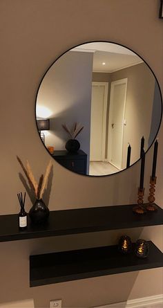 a mirror on the wall above a shelf with candles