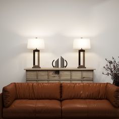 a brown leather couch sitting under two lamps