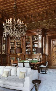 a living room filled with lots of furniture and a chandelier hanging from the ceiling