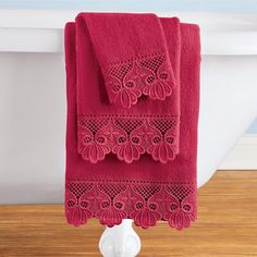 a red towel hanging on the side of a bath tub