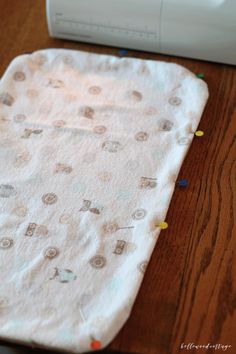 a baby changing mat sitting on top of a wooden table next to a sewing machine