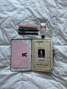 the contents of a book laid out on a white bed sheet, including an envelope, lipstick, and other items