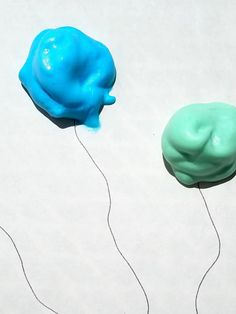 there are two blue and green toy heads on the white surface, one is plugged in