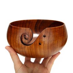 a hand holding a wooden bowl with an intricate design