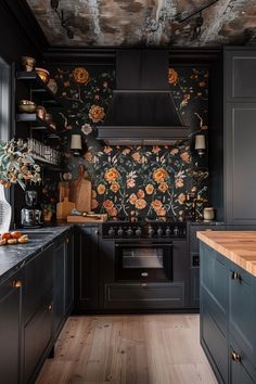 a kitchen with black cabinets and flowers on the wall behind the stove, along with wooden flooring