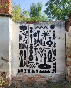 a wall painted with black and white designs on it's side in front of a brick building