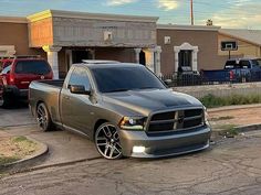 a silver truck parked in front of a building next to other cars on the street