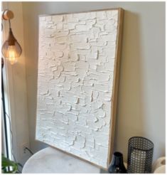 a white toilet sitting next to a wooden framed wall hanging on the side of a wall