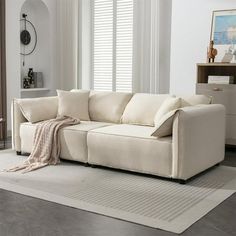 a white couch sitting on top of a rug in a living room next to a window